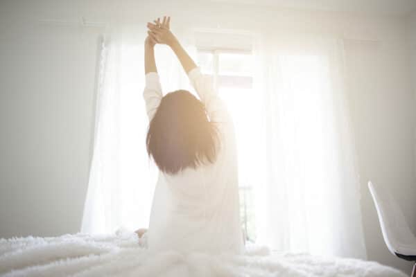 an asian woman stretching as she wakes up in the morning