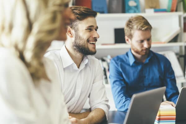 a man smiling during a meeting with his two colleagues