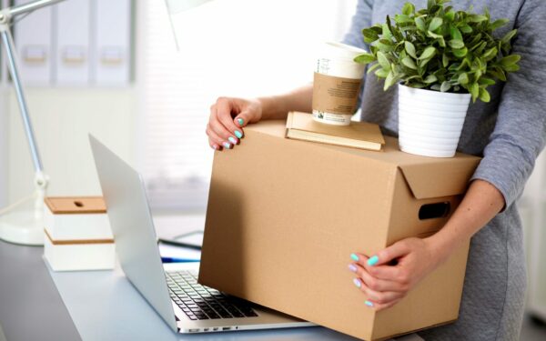 A business woman placing her cardboard box on top of a laptop