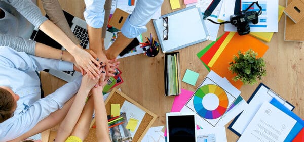 Co-workers putting their hands together at their work station