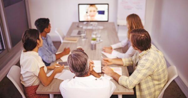A group of co-workers in a conference room watching a video.