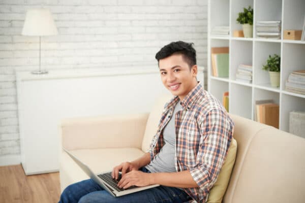 a smiling asian man remotely working from home
