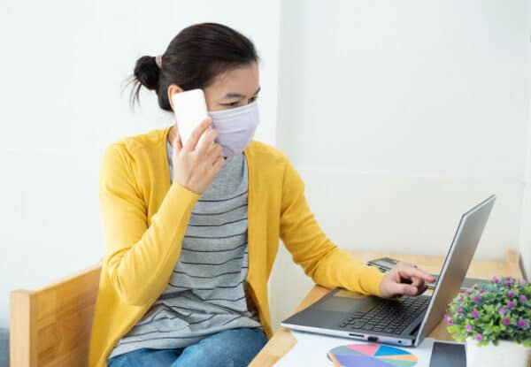 An asian woman wearing a facemask while talking on the phone