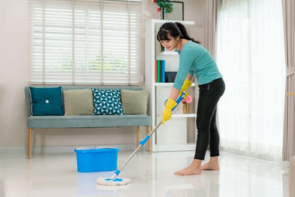 an asian woman mopping the floor of her living room