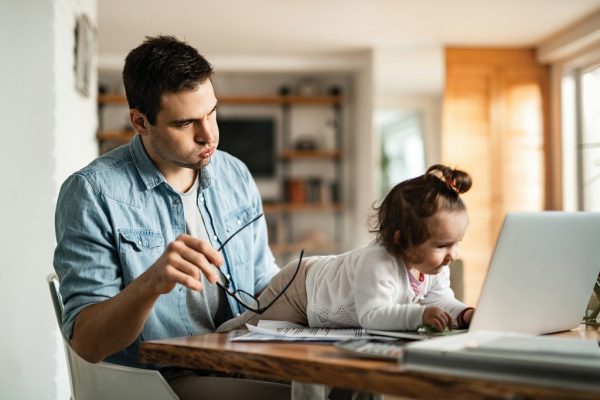 a man being distracted by his daughter while he tries to work from home