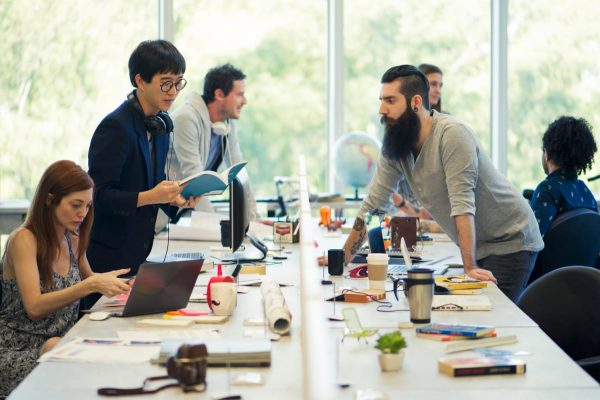 work colleagues talking on their shared desk space