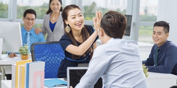 Two colleagues doing a high five in an office