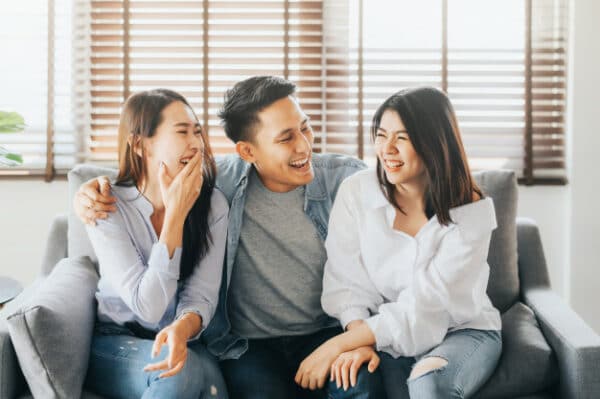 a group of asian friends having fun while sitting on a sofa