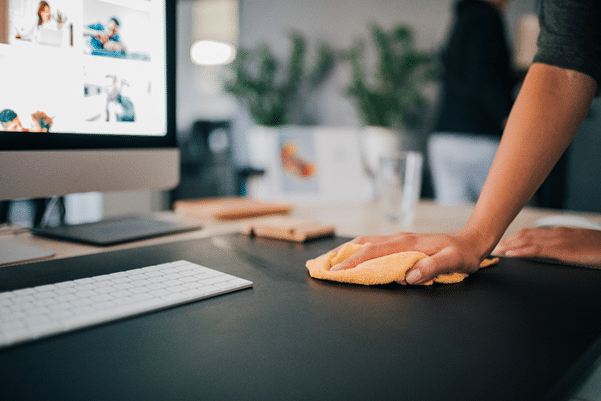 a person wiping an office desk with a cloth