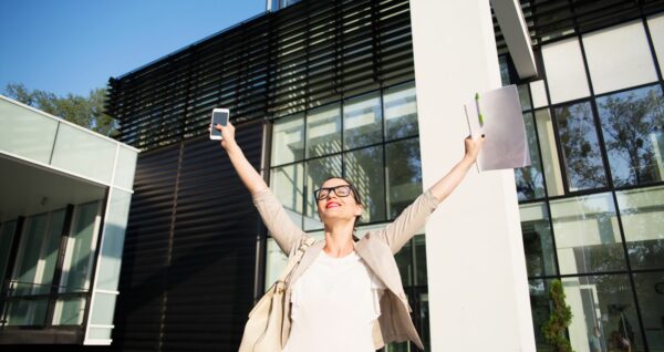 A business woman raising her hands in the air in relief