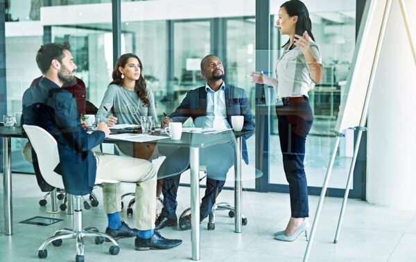 a woman presenting to her team in a meeting room