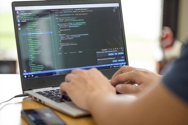A programmer typing code in his laptop