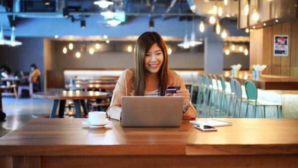 an asian woman putting in her card details on her laptop