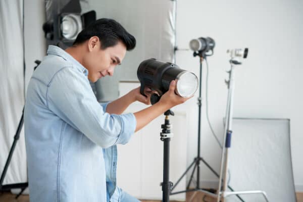 a smiling asian photographer setting up his camera
