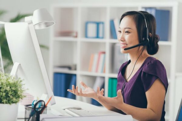 a smiling asian teaching teacher online from home